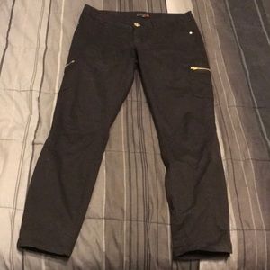 Black pants with gold zipper pocket detail.